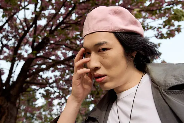 A young Asian man showcases his stylish grey outfit while enjoying a sunny day in the park. — Stock Photo