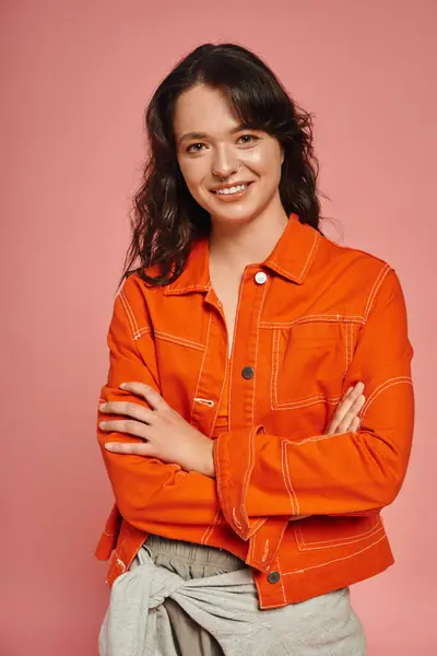 A young woman in a trendy orange jacket smiles warmly, showcasing her fashion sense. — Stock Photo