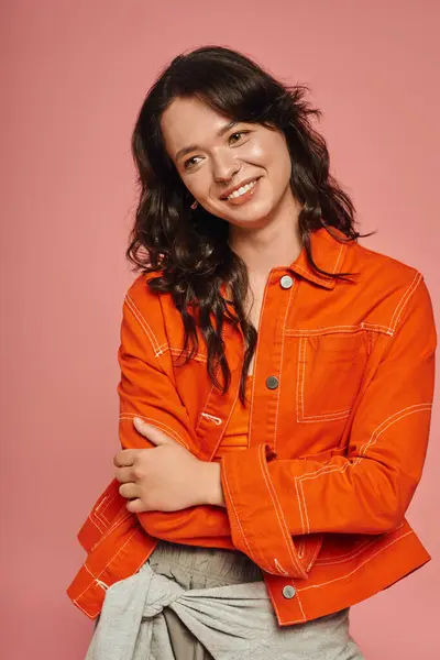 Charming woman exudes confidence while wearing a trendy orange jacket, smiling brightly. — Stock Photo