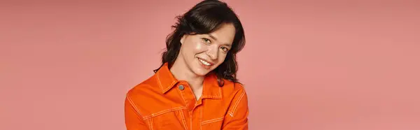 A young woman showcases her trendy orange attire while smiling warmly, exuding style and charm. — Stock Photo