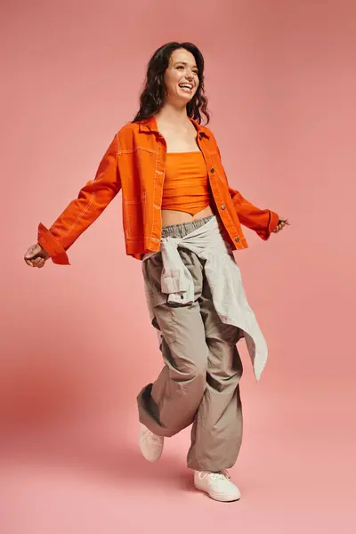 A confident young woman walks gracefully in trendy attire highlighting her unique style. — Stock Photo