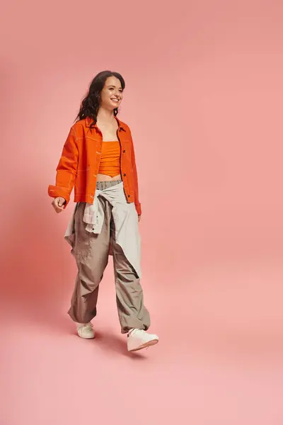 A young woman confidently shows off her trendy outfit while walking gracefully. — Stock Photo