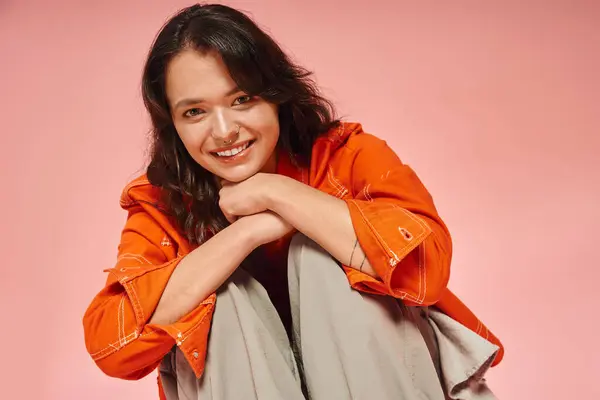 A young woman showcases her unique fashion sense while smiling warmly and sitting casually. — Stock Photo