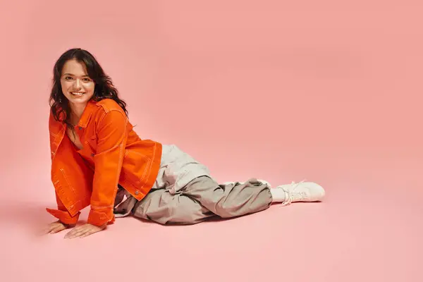 A young woman smiles in a trendy outfit against a vibrant backdrop. — Stock Photo
