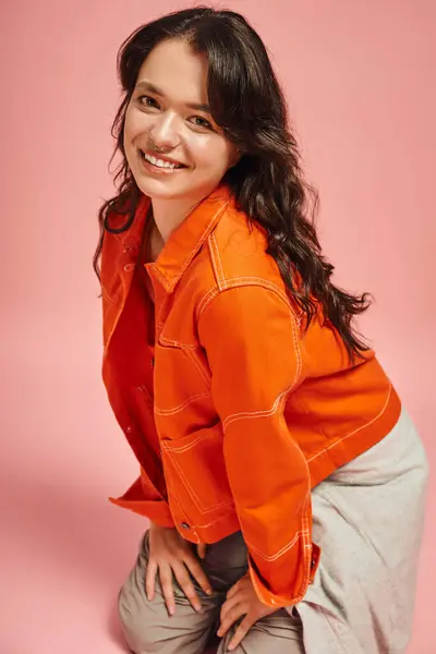 A young woman in a chic orange jacket smiles brightly, expressing her trendy fashion sense. — Stock Photo