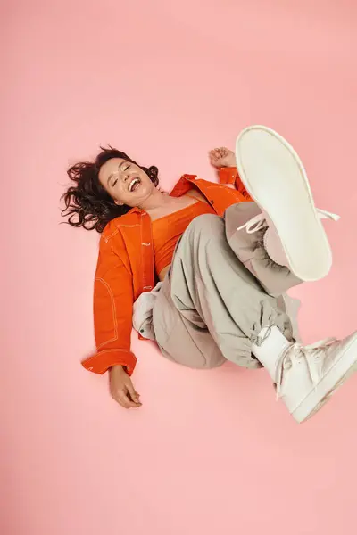 Stylish female relaxes on the floor, showcasing her fashionable attire and radiant smile. — Stock Photo