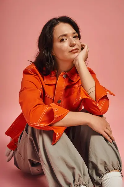 A young beautiful woman poses thoughtfully, highlighting her chic outfit amidst a colorful setting. — Stock Photo