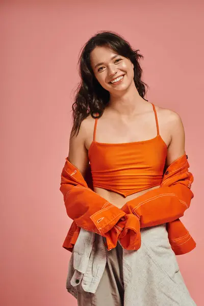 A young woman showcases her fashion sense with a bright orange outfit, smiling and posing happily. — Stock Photo