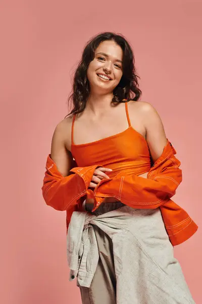 Mujer con estilo muestra su sentido de la moda en una parte superior naranja y atuendo relajado, exudando encanto. - foto de stock
