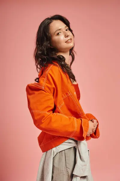 In a lively pink background, a beautiful woman embodies modern fashion with confidence and flair. — стоковое фото
