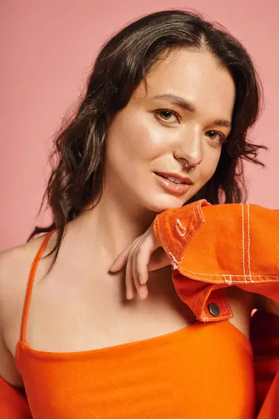 A stylish woman poses confidently in a trendy orange outfit, flashing a captivating smile. — Stock Photo