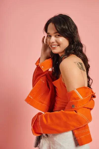 A fashionable young woman showcases her style in an orange outfit, radiating joy and charm. — Stock Photo