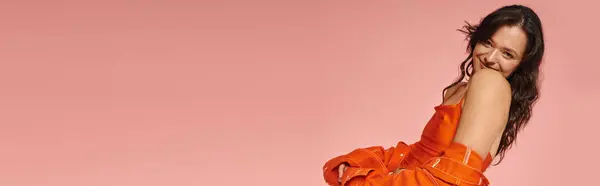 A young woman exudes confidence and style in an eye catching orange outfit as she poses playfully. — Stock Photo
