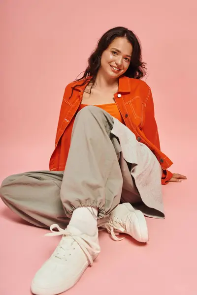 A fashionable young woman relaxes while showcasing her trendy outfit and joyful smile. — Stock Photo