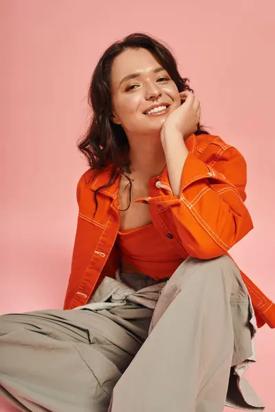 Stylish young woman exudes confidence in chic attire against a vibrant pink background. — Stock Photo