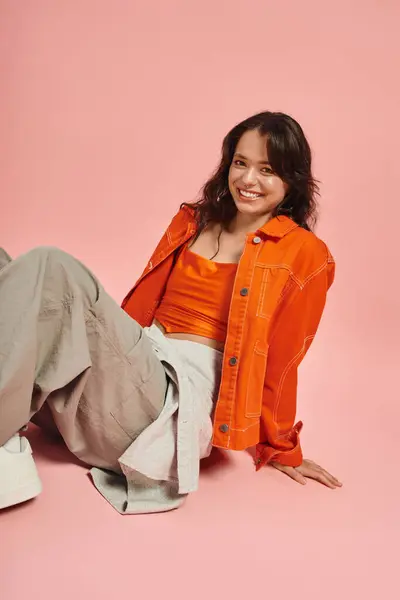 A young woman exudes confidence in a fashionable orange ensemble, smiling radiantly. — Stock Photo