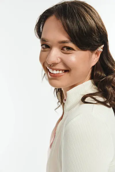 A fashionable young woman smiles confidently, reflecting modern style in a well lit studio space. — стоковое фото