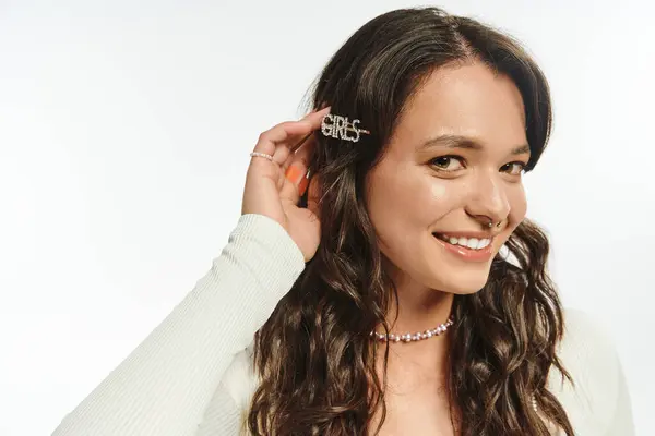 Junge Frau lächelt beim Spielen mit schicken Haaraccessoires vor sauberem Hintergrund. — Stockfoto