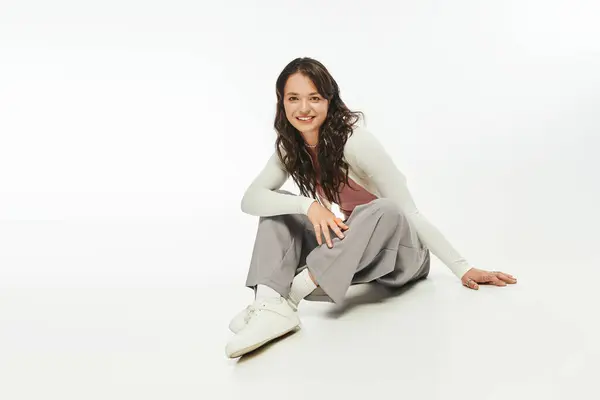 Modische junge Frau strahlt Charme und Eleganz aus, während sie anmutig auf einer sauberen Oberfläche sitzt. — Stockfoto