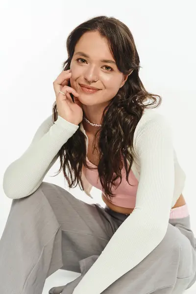 Fashionable young woman showcases her trendy outfit while smiling cheerfully in bright light. — Stock Photo