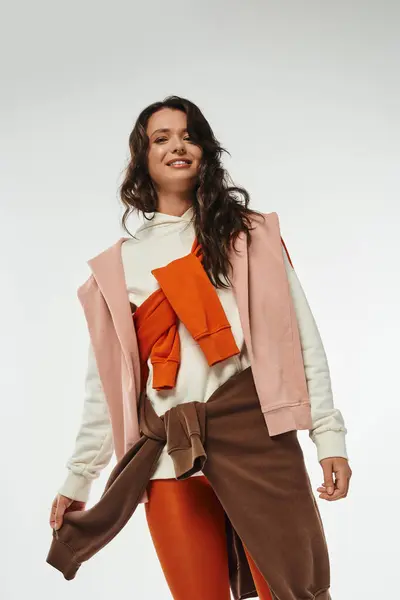 Una mujer joven con estilo muestra con confianza trajes en capas de moda en colores vibrantes. - foto de stock