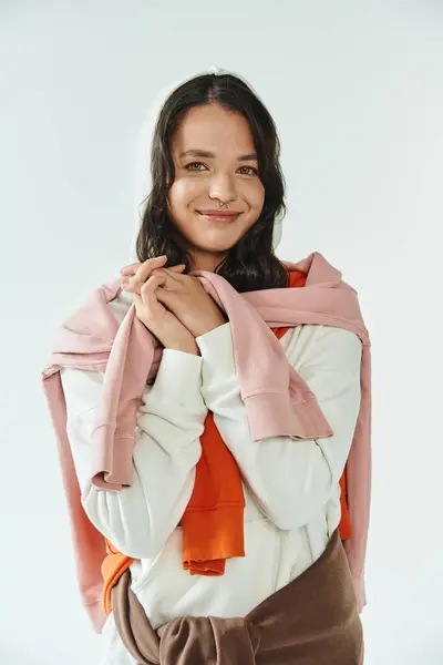 Young woman showcases trendy layered attire, radiating joy and individuality in a well lit space. — Stock Photo
