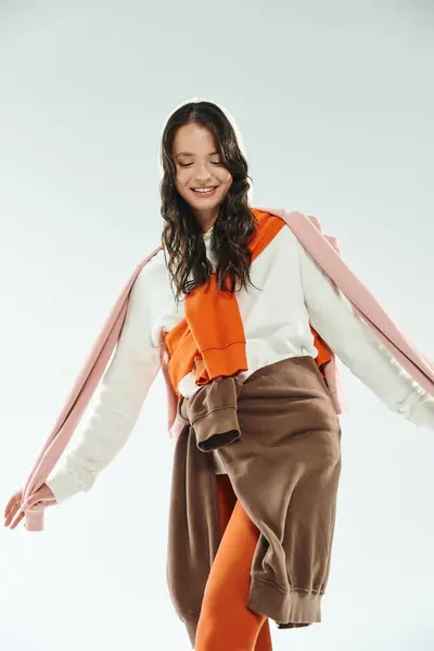 A young woman playfully poses in trendy attire, highlighting her unique style in a bright studio. — Stock Photo