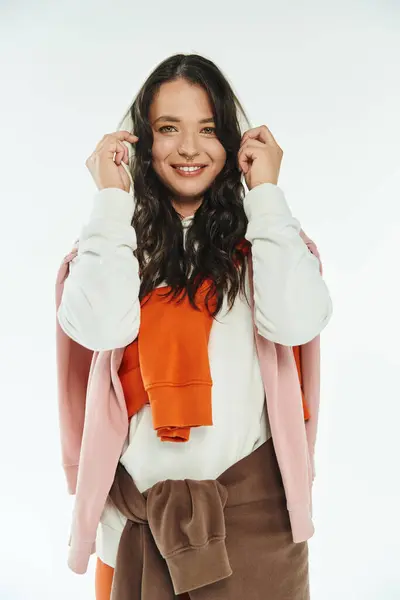 Una joven de moda sonríe mientras ajusta su elegante atuendo en un vibrante estudio. - foto de stock