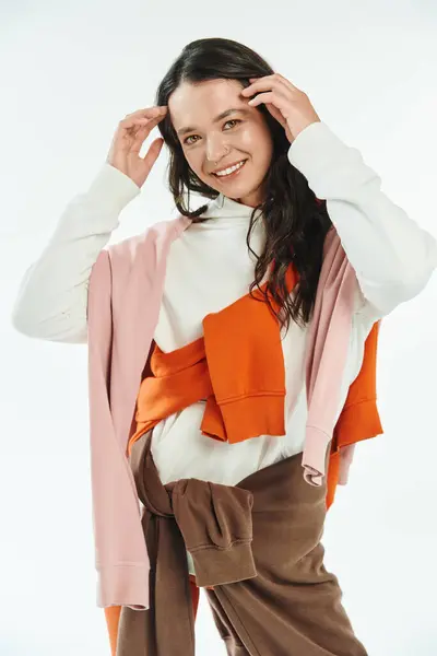 A young woman in fashionable attire smiles while adjusting her stylish outfit in a bright space. — Stock Photo