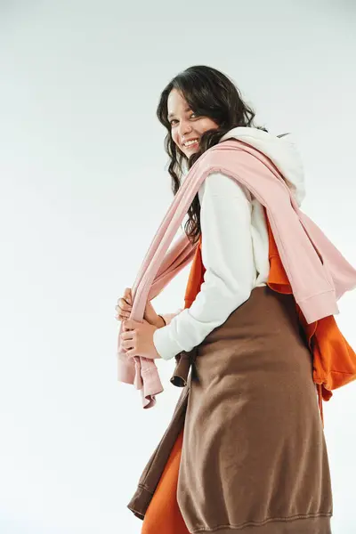 A stylish young woman smiles, playfully arranging her vibrant outfit with confidence. — Stock Photo