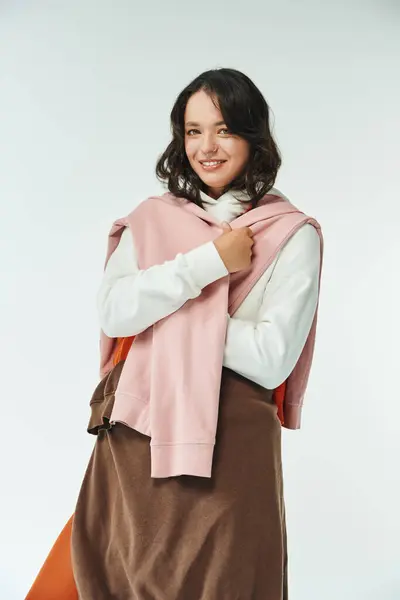 Brightly dressed young woman beams with confidence in a chic outfit against a subtle backdrop. — Stock Photo