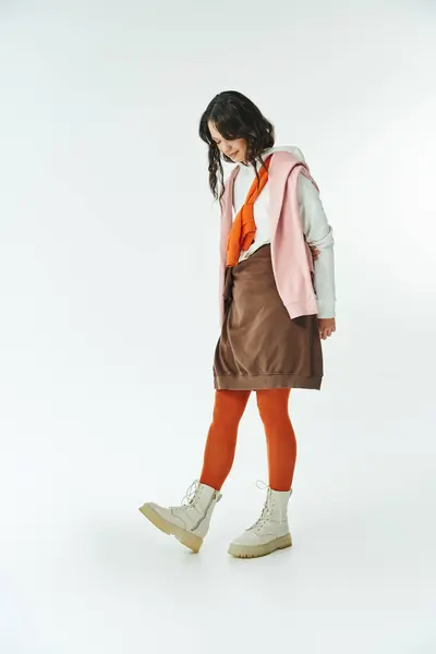 A young woman elegantly displays her fashionable outfit with vibrant hues in a stylish studio. — Stock Photo
