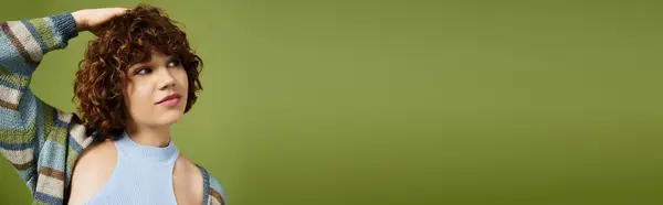 A young woman with short curls poses confidently in a trendy summer outfit against green, banner — Stock Photo