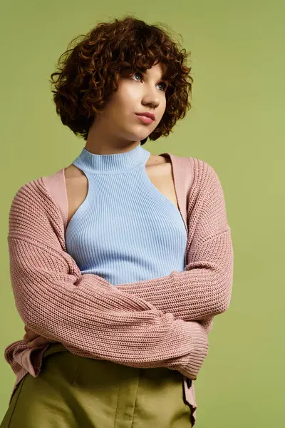 Fashion-forward young woman in a chic summer outfit poses confidently on a vibrant green background. — Stock Photo