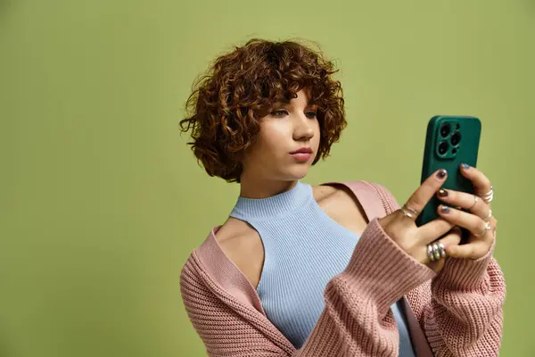 A young woman with short curly hair enjoys a moment of style and technology in a chic outfit. — Stock Photo