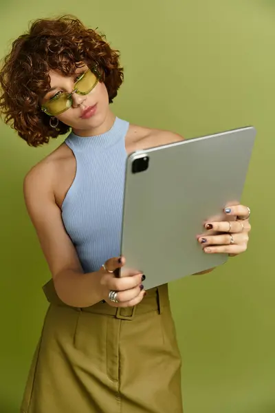 Confident young woman with curly hair engaging with a tablet in studio — Stock Photo