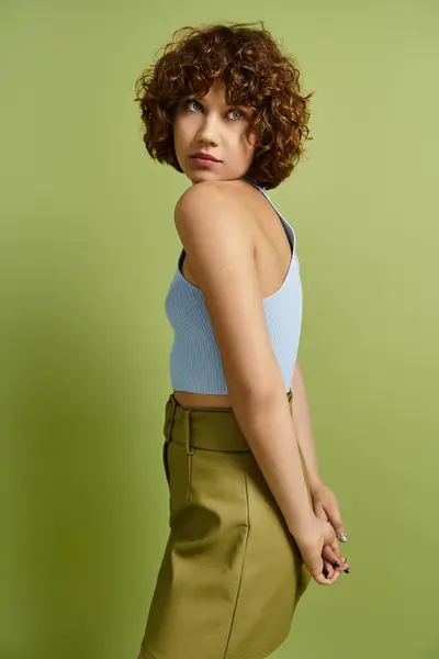 A young woman with curly hair poses gracefully in a stylish summer outfit, radiating confidence. — Stock Photo