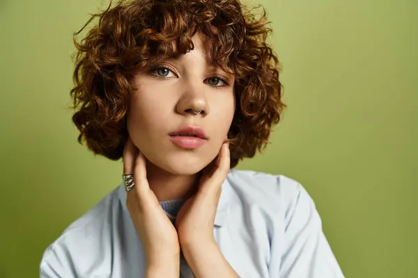 A young woman with short curls poses in a stylish summer outfit against a green backdrop. — Stock Photo