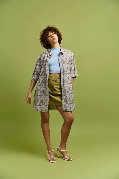 A young woman poses confidently in a stylish summer outfit with a green background. — Stock Photo