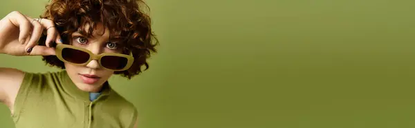 Curly-haired woman poses confidently in trendy summer attire on a fresh green background, banner — Stock Photo