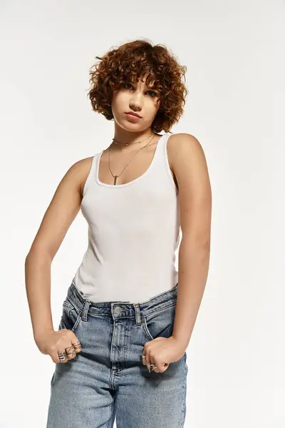 Una joven con el pelo rizado corto muestra su estilo de verano en una camiseta sin mangas y jeans. — Stock Photo