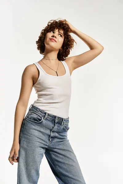 A young woman with curly hair showcases her summer look in a tank top and jeans. — Stock Photo