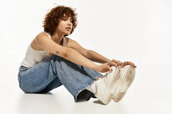 Una mujer joven se sienta en el suelo, estirando las piernas y mostrando su sentido de la moda. — Stock Photo