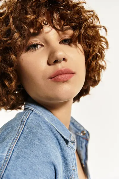 Una mujer joven con el pelo rizado y piercing en la nariz exuda confianza mientras usa una camisa de mezclilla — Stock Photo