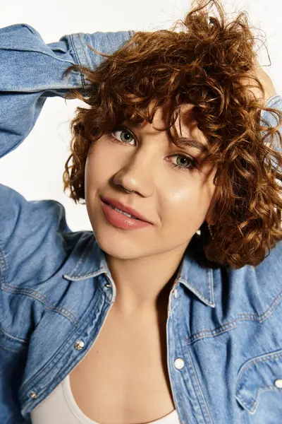 Una mujer joven con el pelo rizado corto posa con confianza en el traje de mezclilla, irradiando vibraciones de verano. — Stock Photo