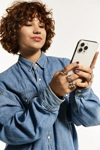 A stylish young woman with short curly hair poses confidently, showcasing her trendy denim outfit. — Stock Photo