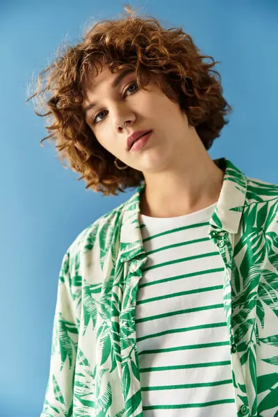 A young woman with short curly hair elegantly poses in a vibrant outfit amid a blue backdrop. — Stock Photo