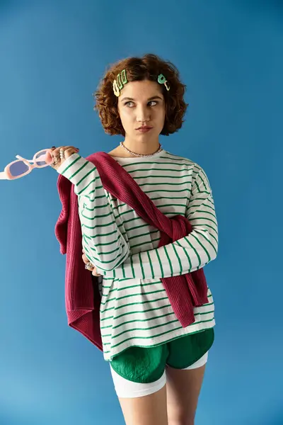 A young woman with short curly hair showcases her unique summer fashion in a playful setting. — Stock Photo
