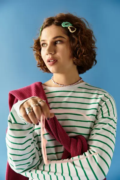 A young woman with short curly hair showcases a vibrant outfit against a blue backdrop. — Stock Photo