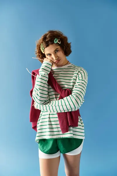 A young woman showcases her vibrant outfit, radiating seasonal freshness against a blue backdrop. — Stock Photo